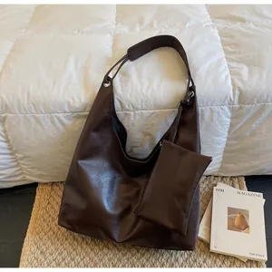 Close-up of vintage brown large hobo bag with matching zipper pouch on white bedding