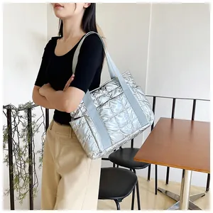 Detail einer glänzenden silbernen Stepptasche mit breiten Trägern in einem Café-Ambiente