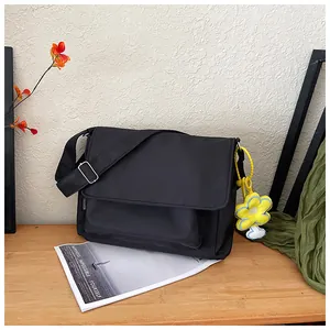 Détail du sac bandoulière en nylon noir avec breloque fleur jaune et boucle