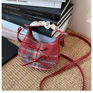 Detail view of red plaid mini crossbody bag with leather bows and lace trim on books