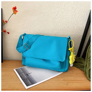 Détail du sac bandoulière en nylon bleu vif avec un pendentif fleur jaune