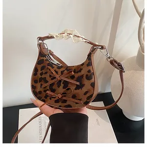 Detail of leopard print crossbody bag with leather bows and delicate white lace trim handle