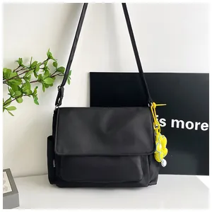 Détail du sac bandoulière en nylon noir avec breloque tournesol jaune et poche latérale