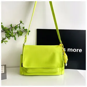 Détail de la sacoche en nylon vert fluo avec étiquette mode et breloque peluche