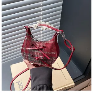 Detail of red wool moon bag with bows and lace handle held by hand for scale