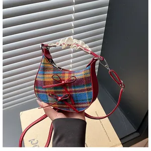 Detail of checkered plaid mini bag featuring red leather trim and lace handle accents