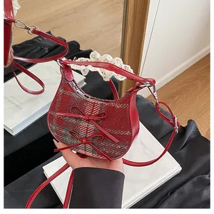 Detail of red plaid crossbody bag with bows and lace handles shown in a mirror