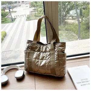 Detailaufnahme der champagnergoldenen Stepptasche mit Seitentasche auf einer Fensterbank