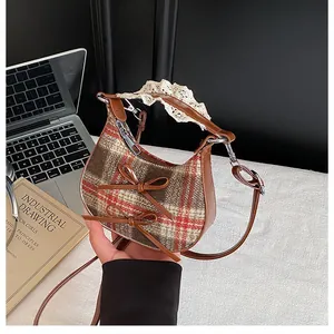 Detail of checkered woolen crescent bag with leather bows and lace-trimmed handle