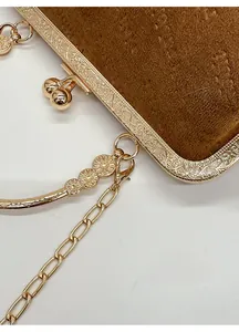 Detail eines goldenen Metallrahmens mit Relief und Schnappverschluss an brauner Wildledertasche