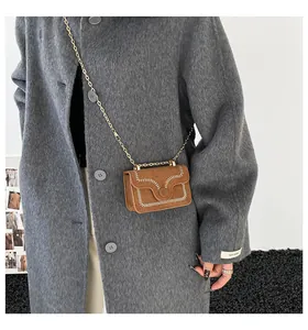 Detail der braunen Wildleder-Umhängetasche mit weißer V-Naht und goldener Kette