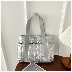 Detail einer silbernen gesteppten Tragetasche mit Metallic-Finish und grauen Griffen