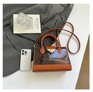 Detail of brown crocodile pattern shoulder bag with gold metal lock and leather handle