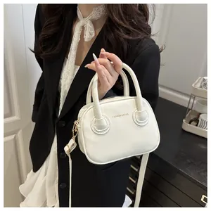 Detalle de mini bolso blanco cruzado con logotipo dorado y textura de cuero para mujer