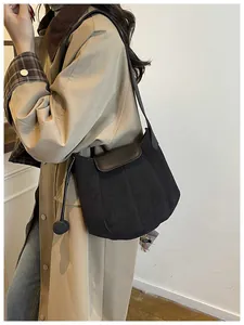 Close-up of matte suede bucket bag with leather flap and plush ball charm accessory