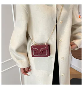 Burgunderrote Wildleder-Umhängetasche mit Wellennaht und Goldkette am Modell