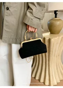 Makroaufnahme einer Retro-Clutch in Schwarz mit graviertem Goldgriff und Kettenriemen