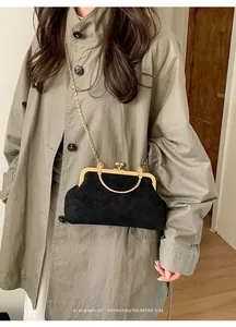 Detail der schwarzen Vintage Umhängetasche mit goldfarbenem Ringgriff zum khakifarbenen Trenchcoat