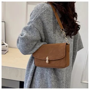 Detailed close-up of brown suede shoulder bag with unique golden peanut shaped metal clasp
