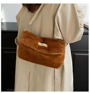 Detail of caramel brown plush faux fur crossbody bag with white rectangular brand tag