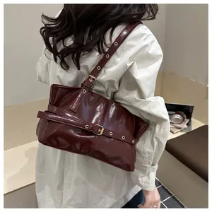 Detail of burgundy oil wax leather tote bag with gold buckle on a model in beige coat
