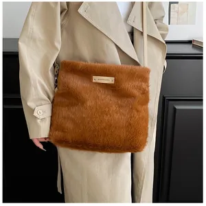 Detail of the golden brand plate on the brown plush faux fur crossbody handbag for winter