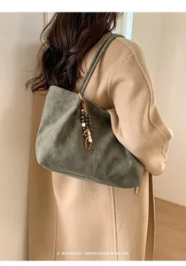Close-up of olive green suede tote bag with retro wooden and monochromatic bead details