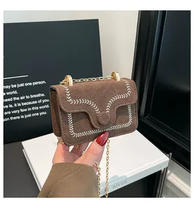 Detail einer braunen Wildleder-Mini-Umhängetasche mit weißen Ziernähten und Goldkette