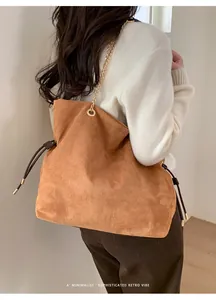 Dettaglio di una borsa a secchiello in camoscio marrone con catena dorata e coulisse