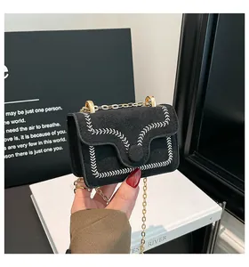 Detail einer schwarzen Wildleder-Mini-Tasche mit weißen Weizennähten und Goldkette