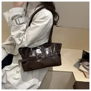 Detailed close-up of dark brown glossy wax leather shoulder bag with decorative eyelet strap
