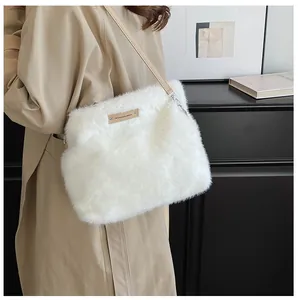 Detailed shot of white faux fur shoulder bag with tan leather strap and logo patch