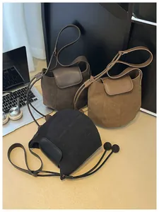 Three suede bucket bags in brown and black colors with spherical charms on a desk