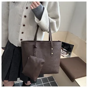 Detail of dark brown tote bag showing smooth leather texture and gold rivet hardware