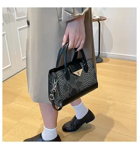 Dettaglio della borsa in pelle a motivo serpente con fibbia a triangolo d'oro su modella