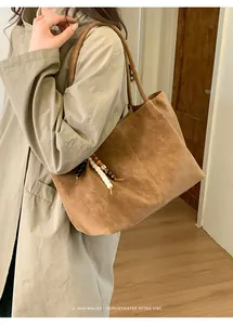 Detail view of brown suede tote bag with boho beaded pendant and minimalist retro vibe