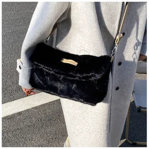 Detail of black faux fur crossbody bag with long strap and small brown brand tag