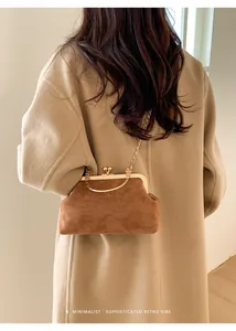 Braune Wildledertasche mit Goldkette getragen über einem beigen Kaschmirmantel