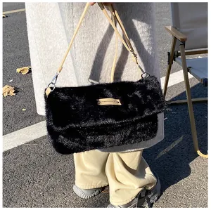 Detail showing the fluffy black faux fur texture and brown leather strap of the bag