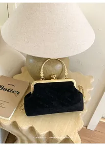 Detail der schwarzen Wildleder-Abendtasche mit goldener Ringgriff und Retro-Verschluss