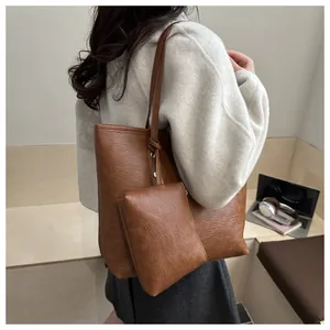 Detail view of brown leather tote bag with matching pouch on model in a workspace setting