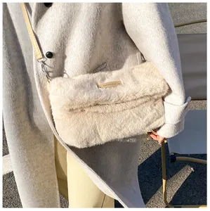 Detail of plush off-white handbag with gold logo plaque and leather shoulder strap