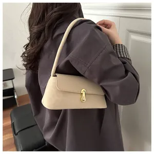 Close-up of cream baguette bag featuring a refined gold capsule metal clasp and leather texture
