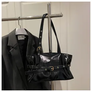 Detail of glossy black oil-wax leather shoulder bag with gold buckle and pleated texture