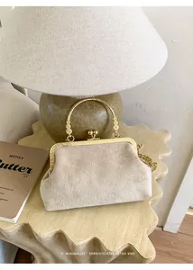 Detail der beigen Wildleder-Abendtasche mit goldenem Ringgriff und Rich Rabbit Prägung