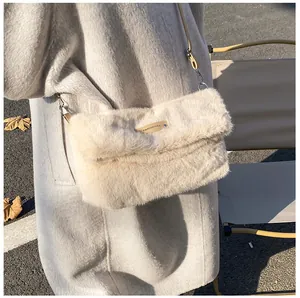 Close-up of beige plush faux fur crossbody bag with logo plate and leather strap