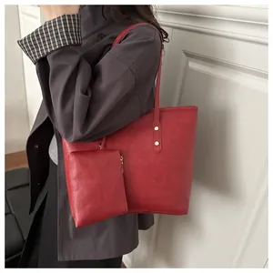Detail of red tote bag featuring gold rivets and a matching small zipper pouch