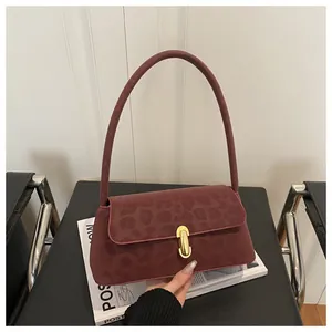 Close-up of burgundy leopard embossed shoulder bag with gold buckle on velvet texture