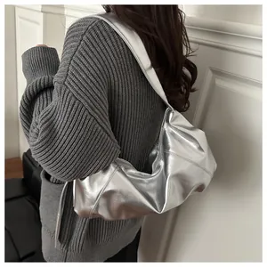 Macro detail of metallic silver shoulder bag featuring textured leather and wide strap design