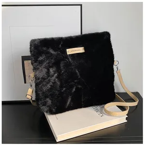 Detail of plush black faux fur texture with brown leather logo tag and shoulder strap